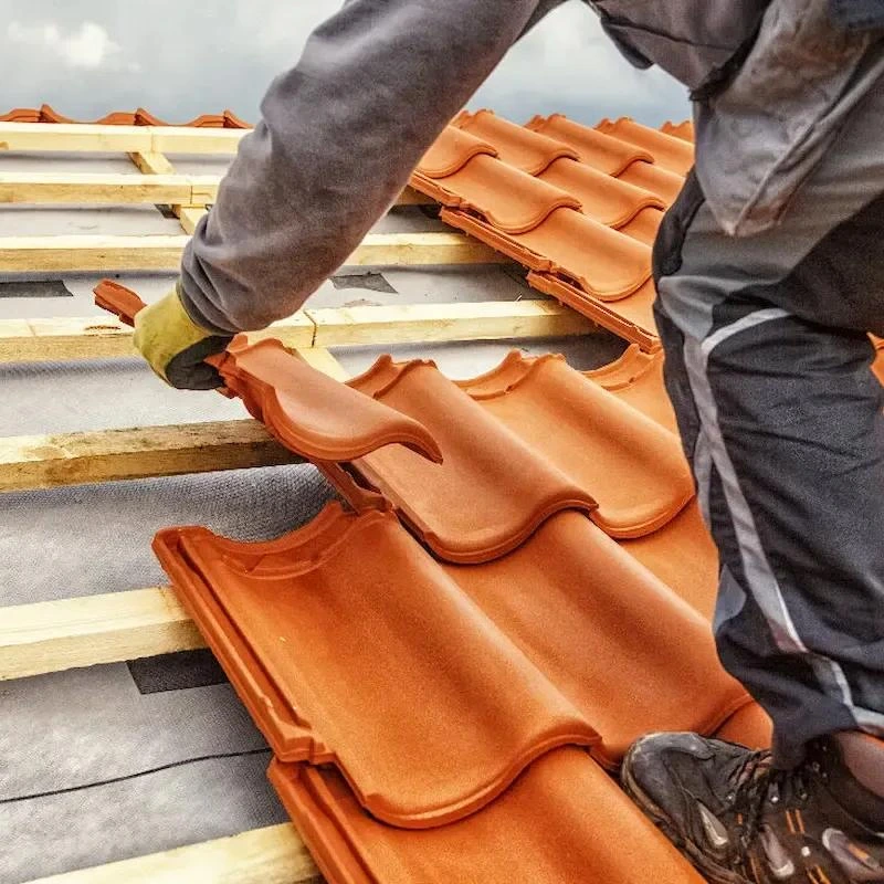 Couvreur à La Palmyre posant des tuiles sur une toiture en construction