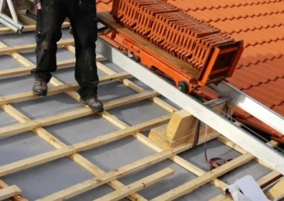 Couvreur en train de poser des tuiles sur une toiture en rénovation